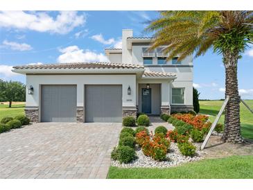 Beautiful two-story home featuring a two-car garage, lovely landscaping, and a healthy palm tree at 16030 Vetta Dr, Bella Collina, FL 34756