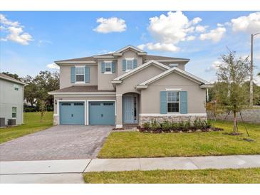 Charming two-story home with a three-car garage, beautiful landscaping, and blue shutters at 2208 Keystone Pass Blvd, Minneola, FL 34715