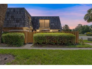 Charming home featuring a unique roof design, lush landscaping, and a welcoming fenced-in front yard at 2920 Poplar Ave, Leesburg, FL 34748
