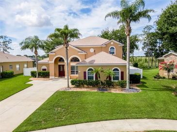 Beautiful two-story stucco home features manicured lawn, decorative shrubs, and mature palm trees in a tropical landscape at 4548 Barrister Dr, Clermont, FL 34711