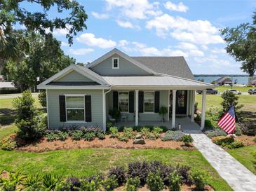 Charming single story home with manicured lawn, covered porch, American flag and water view in the distance at 622 W 11Th Ave, Mount Dora, FL 32757