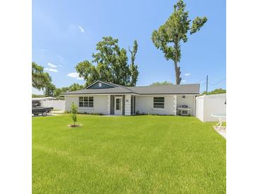 Charming single-story home featuring a manicured lawn, white fence, and inviting entrance at 999 W Juniata St, Clermont, FL 34711