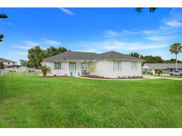 Charming single-story home with a well-manicured lawn, and light blue shutters and front door at 15629 Catherine Cir, Groveland, FL 34736