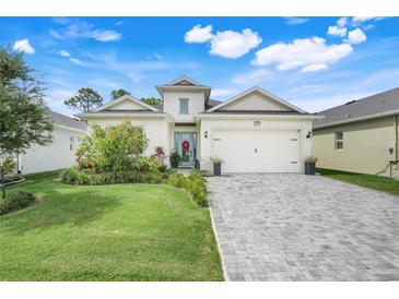 Charming single-story home featuring manicured lawn, brick driveway, and a welcoming front entrance at 1990 Wallingford Loop, Mount Dora, FL 32757