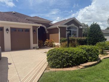 Charming single-story home with a well-manicured lawn and a beautiful tiled driveway leading to a two-car garage at 2994 Adrienne Way, The Villages, FL 32163