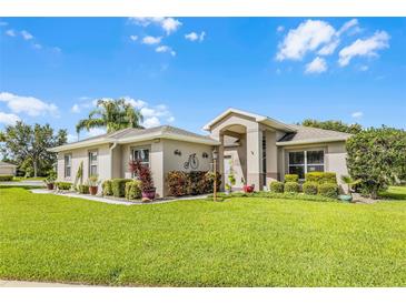 Charming single-story home with a manicured lawn, mature landscaping, and inviting entryway at 5620 Illumination Ln, Leesburg, FL 34748