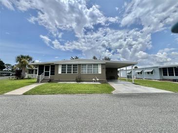 Charming single-story home featuring a carport, well-maintained lawn, and inviting curb appeal on a sunny day at 117 Jacaranda Dr, Leesburg, FL 34748