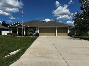 Charming single story home featuring a 3-car garage, manicured lawn, and American flag at 13109 Laurel Crest Ct, Grand Island, FL 32735