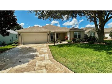 Charming single-story home featuring a manicured lawn, stone driveway, and attached two-car garage at 1412 Forest Acres Dr, The Villages, FL 32162