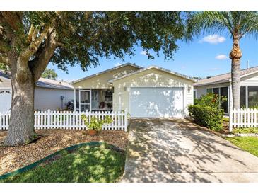 Charming home featuring a white picket fence, mature trees, and attached garage at 16938 Se 94Th Sunnybrook Cir, The Villages, FL 32162