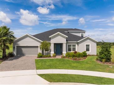 Beautiful single-Gathering home featuring manicured lawn, blue front door, and two car garage at 2161 Cedar Springs Way, Minneola, FL 34715