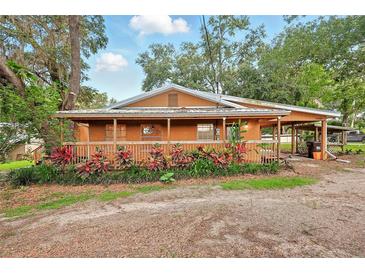 Charming single-story home featuring a cozy porch and well-maintained landscaping and attached covered parking at 25888 Se 157Th Ln, Umatilla, FL 32784
