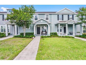 Inviting two-story townhome with well-manicured lawn and charming front porch seating at 520 Rainbow Springs Loop, Groveland, FL 34736