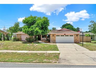 Charming single-story home featuring a brick facade, lush greenery, and a two-car garage at 6316 Marlberry Dr, Orlando, FL 32819