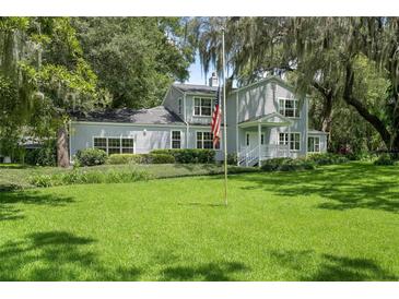 Beautiful two-story home with lush green lawn, mature landscaping, and an American flag displayed in front at 9223 Silver Lake Dr, Leesburg, FL 34788