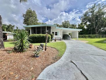 Charming single-story home with a screened-in porch, carport, and well-maintained lawn and landscaping at 113 Temple W Cv, Leesburg, FL 34748