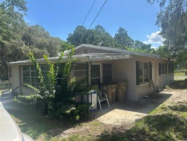 Modest single-story home with a small covered porch and mature landscaping, needs TLC at 11651 Fairmont Ave, Leesburg, FL 34788