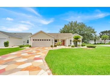Charming single-story home with well-manicured lawn, colorful driveway, and attached two-car garage at 1401 Madrigal Ln, Lady Lake, FL 32159