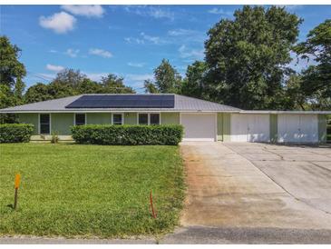 Charming single-story home with a well-manicured lawn, metal roof and three car garage at 2450 W Lake Dr, Deland, FL 32724