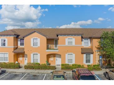A sunny, orange two-story townhome with a brown roof, white trim, and well-maintained landscaping at 2717 Bushman Dr, Kissimmee, FL 34746