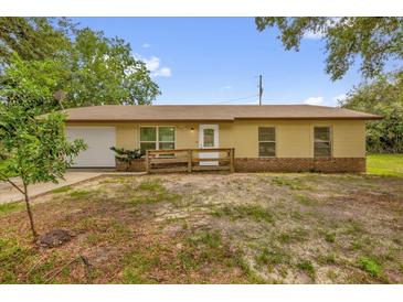 Charming single-story home with a well-maintained yard, front access ramp, and attached garage at 302 W Rose Ln, Lady Lake, FL 32159