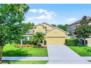 Charming single-Gathering home featuring a well-manicured lawn, mature trees, and a two-car garage at 418 Rock Springs Cir, Groveland, FL 34736