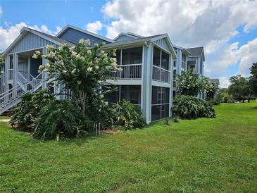 Apartment building featuring screened balconies, lush landscaping, and beautiful flowering trees at 711 Sugar Bay Way # 115, Lake Mary, FL 32746