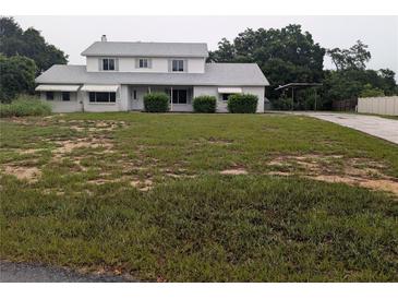 Two-story home featuring a spacious yard, covered parking, and mature trees at 11532 Beaman Cir, Clermont, FL 34711