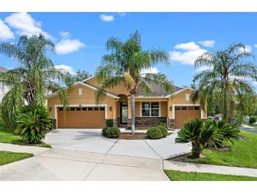 Charming home featuring a three-car garage and a lush yard with mature palm trees at 1892 Sanderling Dr, Clermont, FL 34711