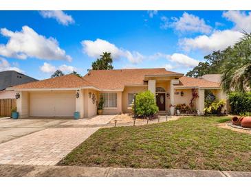 Charming single-story home featuring manicured landscaping, a brick-paved driveway, and a two-car garage at 3309 Paisley Cir, Orlando, FL 32817