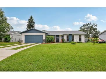 Charming single-story home featuring a well-manicured lawn, blue garage door, and inviting curb appeal at 550 Floral Dr, Kissimmee, FL 34743