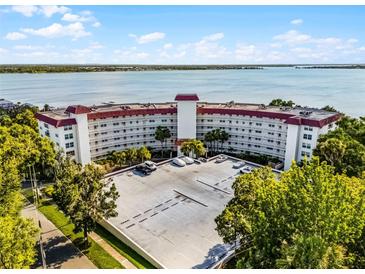 Waterfront condo building featuring a red tile roof, well-maintained landscaping, and ample parking at 601 N Mcdonald St # 2, Mount Dora, FL 32757