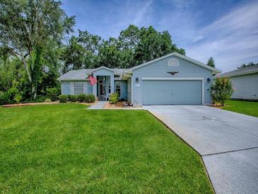 Charming single-story home with a well-manicured lawn, blue siding, and an attached two-car garage at 627 Timbercrest Dr, Leesburg, FL 34748