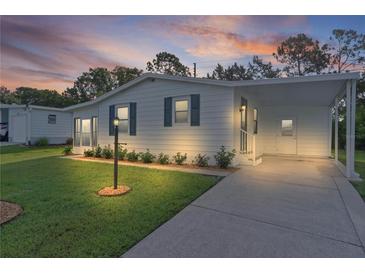 Charming one-story home with fresh white paint, blue shutters, covered parking and a well-maintained lawn at 1421 E Schwartz Blvd, The Villages, FL 32159