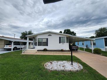 Charming single-story home featuring a well-maintained lawn, white exterior, and convenient covered parking at 163 Sweet Cir, Winter Haven, FL 33884