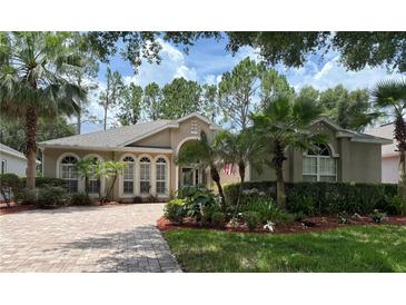Charming single-story home featuring manicured landscaping, a brick driveway, and beautiful arched windows at 2299 Twickingham Ct, Clermont, FL 34711