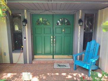 Inviting front entrance featuring a bright green double door and a cheerful blue Adirondack chair at 29205 Old E Ml, Tavares, FL 32778