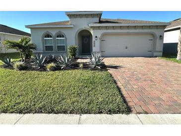 Charming single-story home with a well-manicured lawn, desert landscaping, and a brick driveway at 295 Whirlaway Drive, Davenport, FL 33837