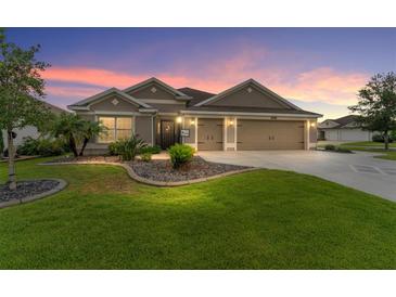 Charming one-story home featuring a well-maintained lawn, mature landscaping, and a spacious three-car garage at 3750 Raspberry Ct, The Villages, FL 32163
