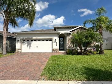 Charming home featuring a brick driveway, stone accents, well-maintained lawn and beautiful curb appeal at 384 Summer Squall Rd, Davenport, FL 33837