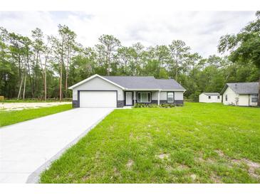 Charming single-story home with attached garage, and a well-manicured lawn at 1243 Ne 130Th Ter, Silver Springs, FL 34488