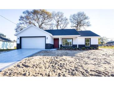 Charming single-story home featuring a well-manicured front yard and a two-car garage at 13050 Ne 7Th Loop, Silver Springs, FL 34488