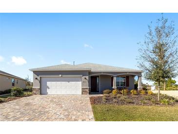 Charming single-story home with a well-manicured lawn, stone accents, and a brick paved driveway at 8731 Sw 76Th Street Rd, Ocala, FL 34481