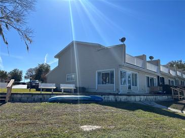 Tan colored house with a kayak and benches near the water at 11001 Se Sunset Harbor Rd # B09, Summerfield, FL 34491