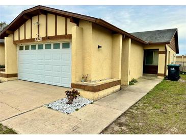 Tan house with white garage door and landscaping at 1328 Spring Lite Way, Orlando, FL 32825