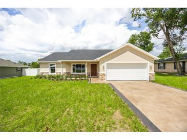 Charming single-story home with a well-manicured lawn, stone accents, and an attached two-car garage at 741 Ne 130Th Ter, Silver Springs, FL 34488