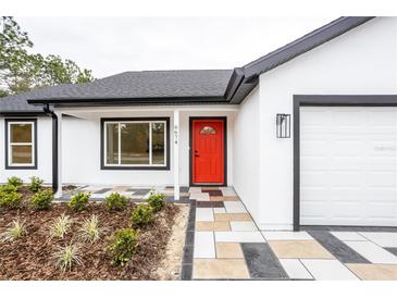 Charming home featuring a bright red front door, tiled entryway, and fresh landscaping at 741 Ne 130Th Ter, Silver Springs, FL 34488