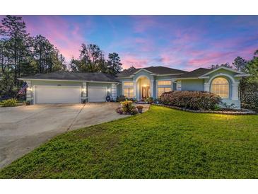 Exterior image featuring a manicured lawn, circular driveway, and three-car garage at 12880 Sw 66Th St, Ocala, FL 34481