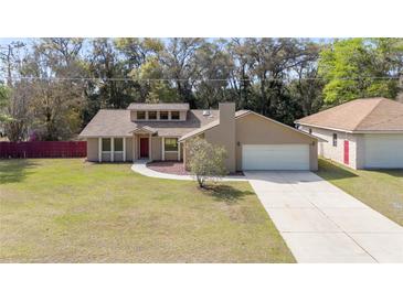 Charming single-Gathering home showcasing a spacious yard, a two-car garage and a beautiful red door at 5238 Ne 1St Ave, Ocala, FL 34479