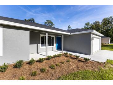 Inviting one story home featuring a blue front door, fresh landscaping, and an attached one car garage at 24009 Sw Huckleberry Ln, Dunnellon, FL 34431